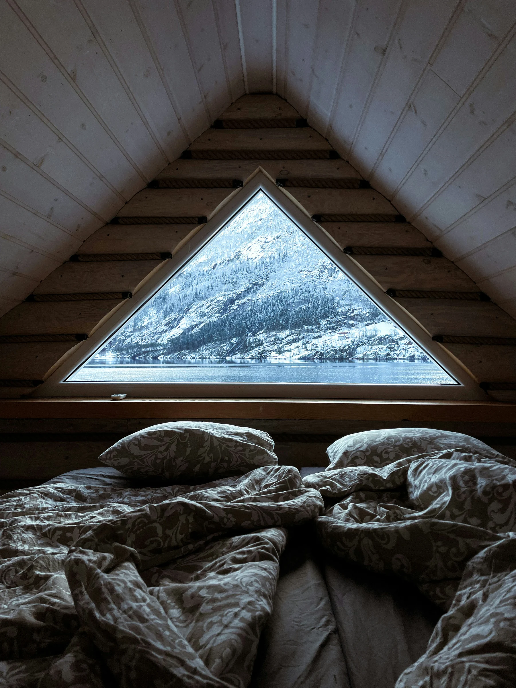 Chambre chaleureuse avec mobilier en bois et vue sur les montagnes depuis une large fenêtre.