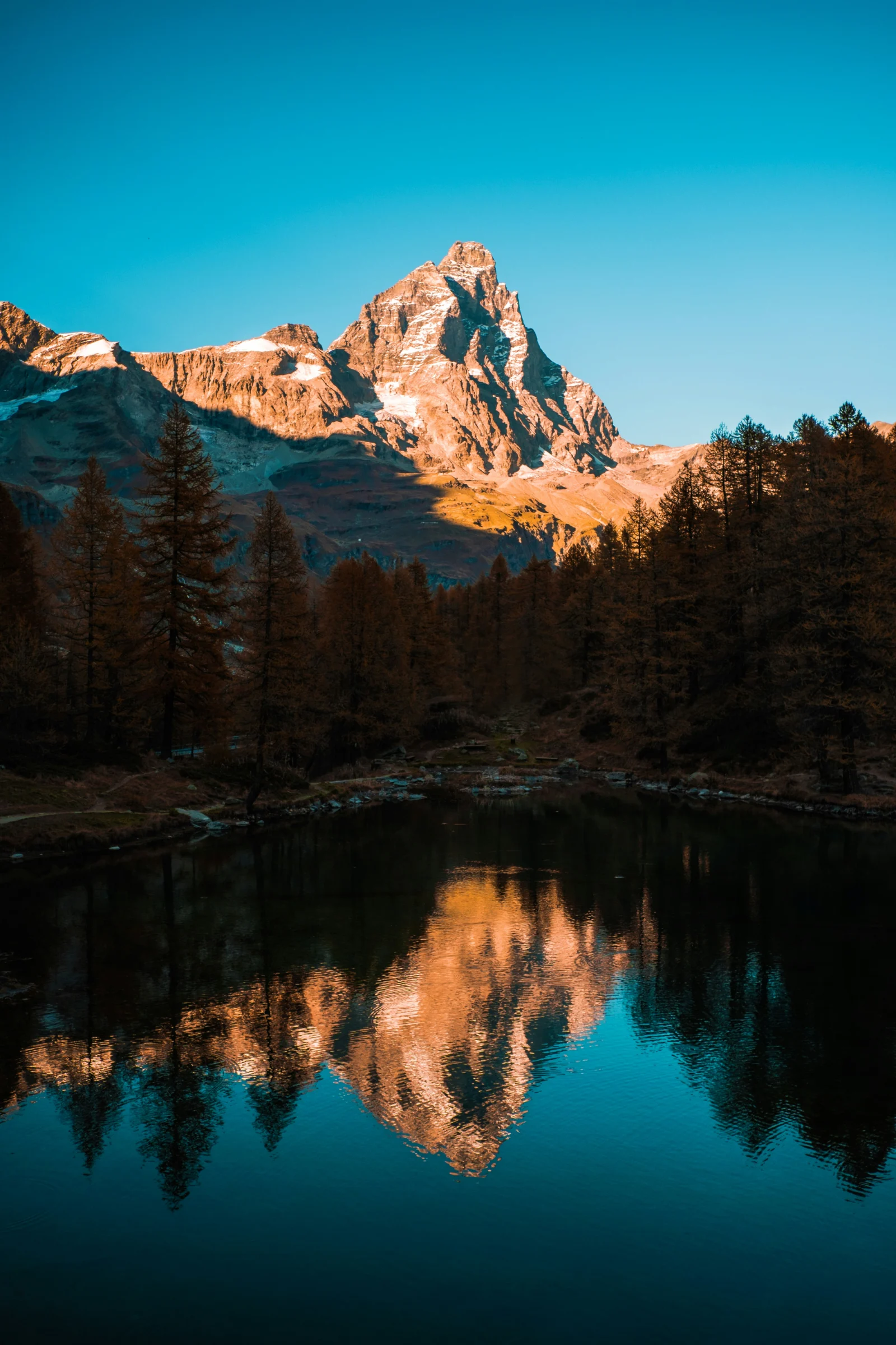 Lac entouré de montagnes et de forêts aux couleurs d’automne.